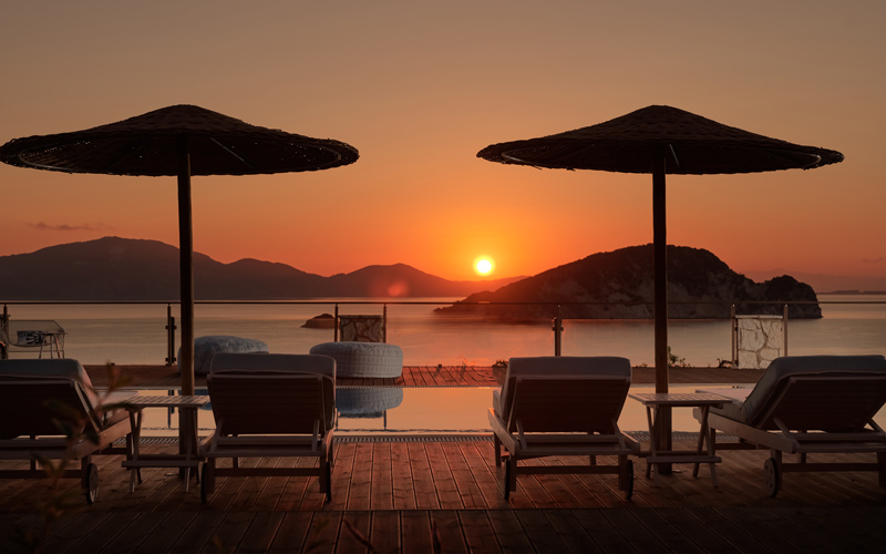 sunbeds by the pool and sea view at sunset
